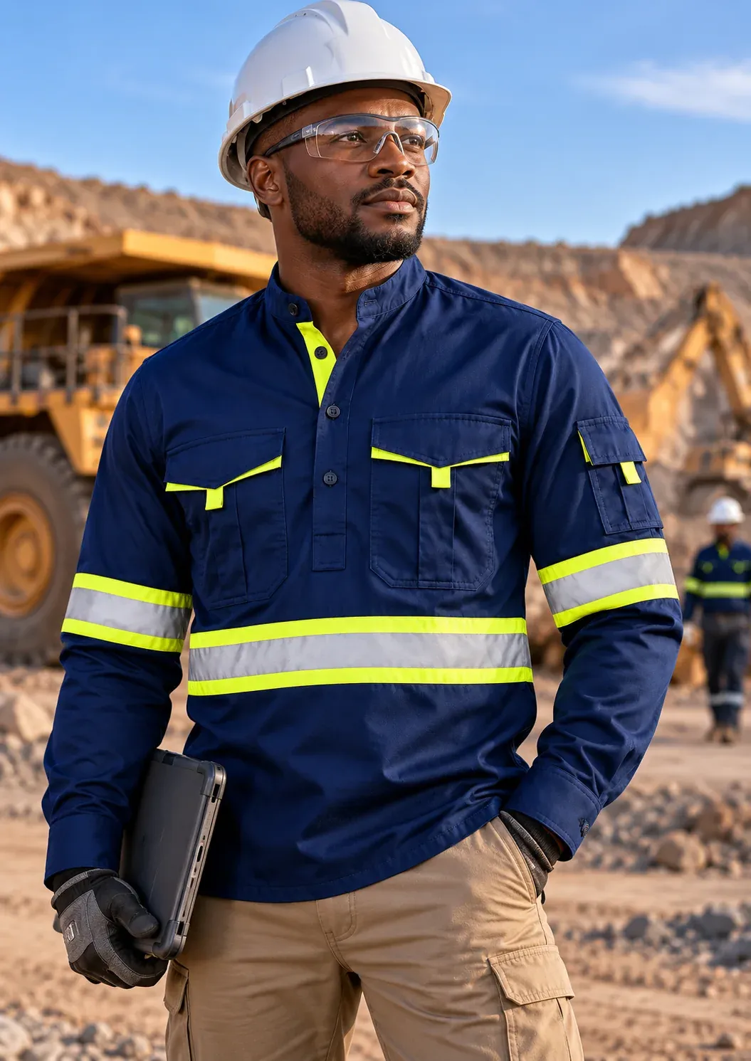 A worker in a navy long-sleeve Standout shirt with lime reflective trim and a hard hat, at a mine site